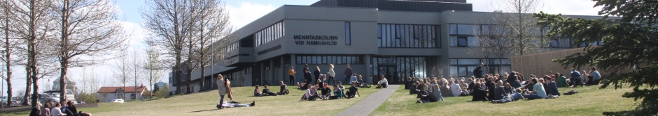 Menntaskólinn við Hamrahlíð - nemendur sitja á grasinu við hlið byggingar skólans
